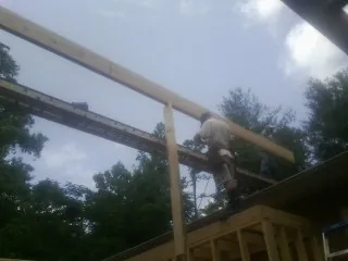 Carpenter setting a ridge beam over a new addition frame — Ice Dam Removal by Roofing Brothers in Saint Louisville
