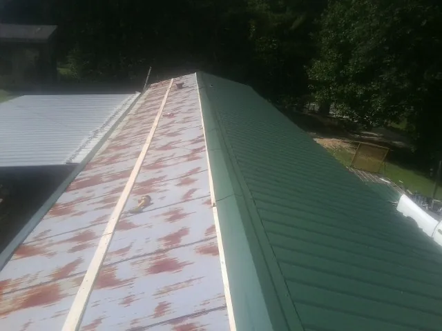 Old rusted panels beside newly installed green metal roofing — Wind Damage Roof Repair by Roofing Brothers in Saint Louisville