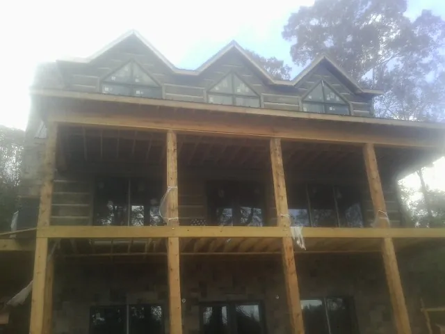 Dormers and porch framing on a large log home under construction — Roof Coating work by our crew in Saint Louisville