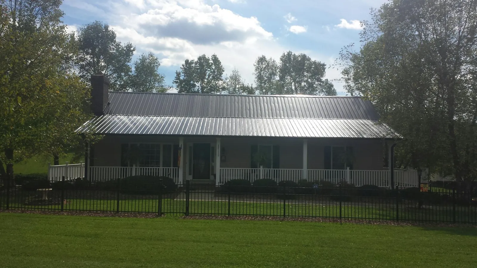 Gray metal roof on a brick ranch with a full width front porch — Gutter Guard Installation work by our crew in Saint Louisville