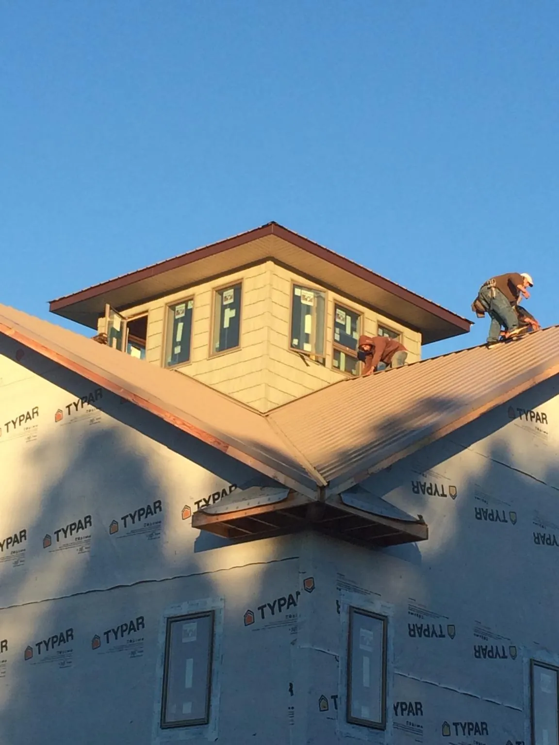 Roofers working around a rooftop cupola on a new metal roof at sunset — Roof Waterproofing in Saint Louisville by Roofing Brothers